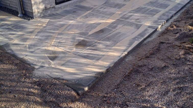 Ny betonoverflade på en terrasse med grus omkring, der viser en glat og ensartet finish.