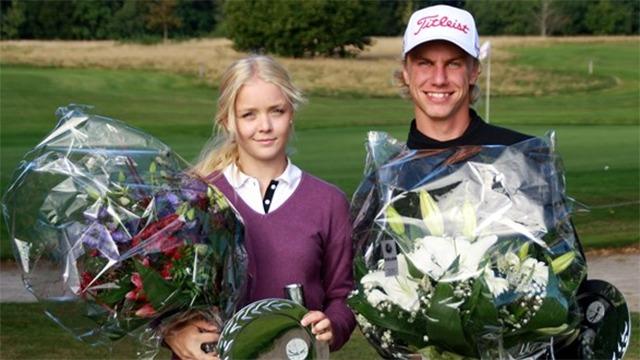 To unge golfspillere står sammen med store blomsterbuketter og præmier efter en turnering.