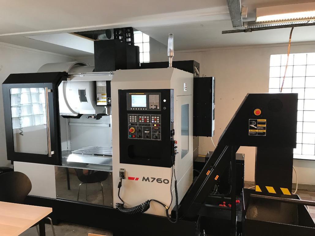 Billede af en M750 CNC-maskine i et moderne værksted med kontrolpanel og arbejdsområde.