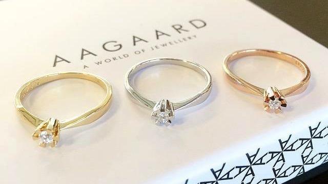 Tre elegante forlovelsesringe i guld, sølv og rosaguld med diamanter, præsenteret på en Aagaard smykkeæske.