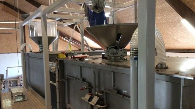 Industrielt udstyr i en fabrikshal med to store tragtformede beholdere til materialeflow.