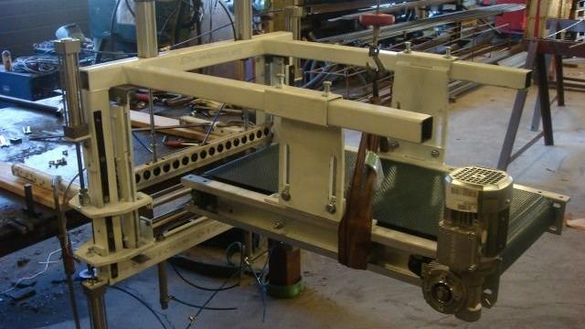Billede af en metalbearbejdningsmaskine med motor og justerbare dele i et værksted.