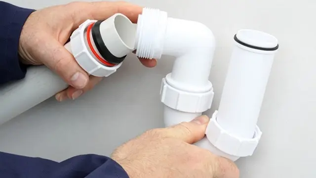 Hånd, der samler hvide PVC-rør og fittings til VVS-installation.