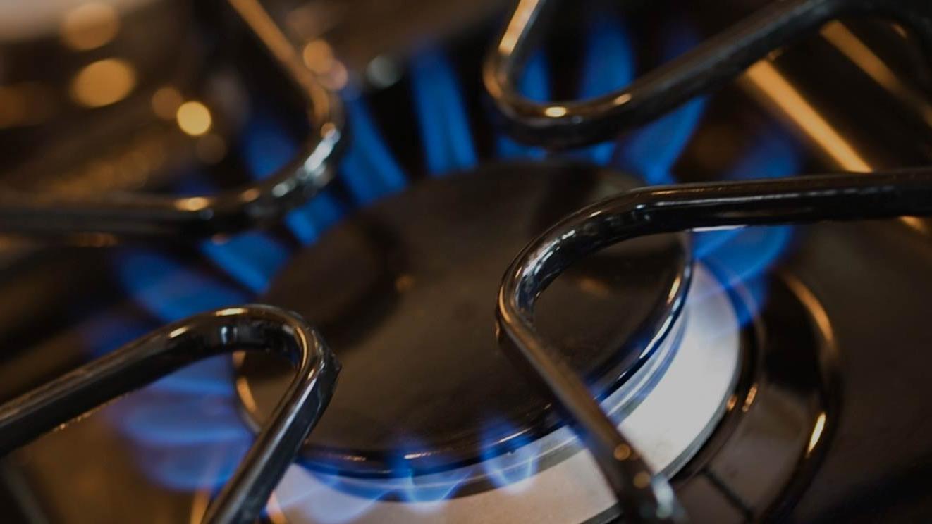 Gasblus med blå flamme tændt, der viser det varme element på en gaskomfur.