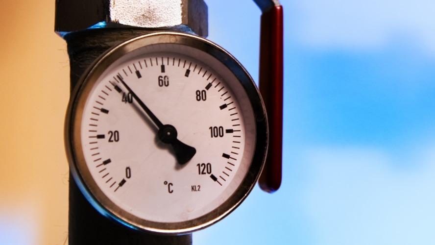 Manometer med en skala fra 0 til 120 grader Celsius, monteret på en rørledning.