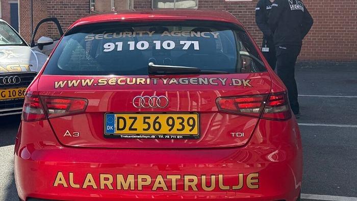 Rød Audi med teksten "SECURITY AGENCY" og telefonnummeret 91101071 på nummerpladen.