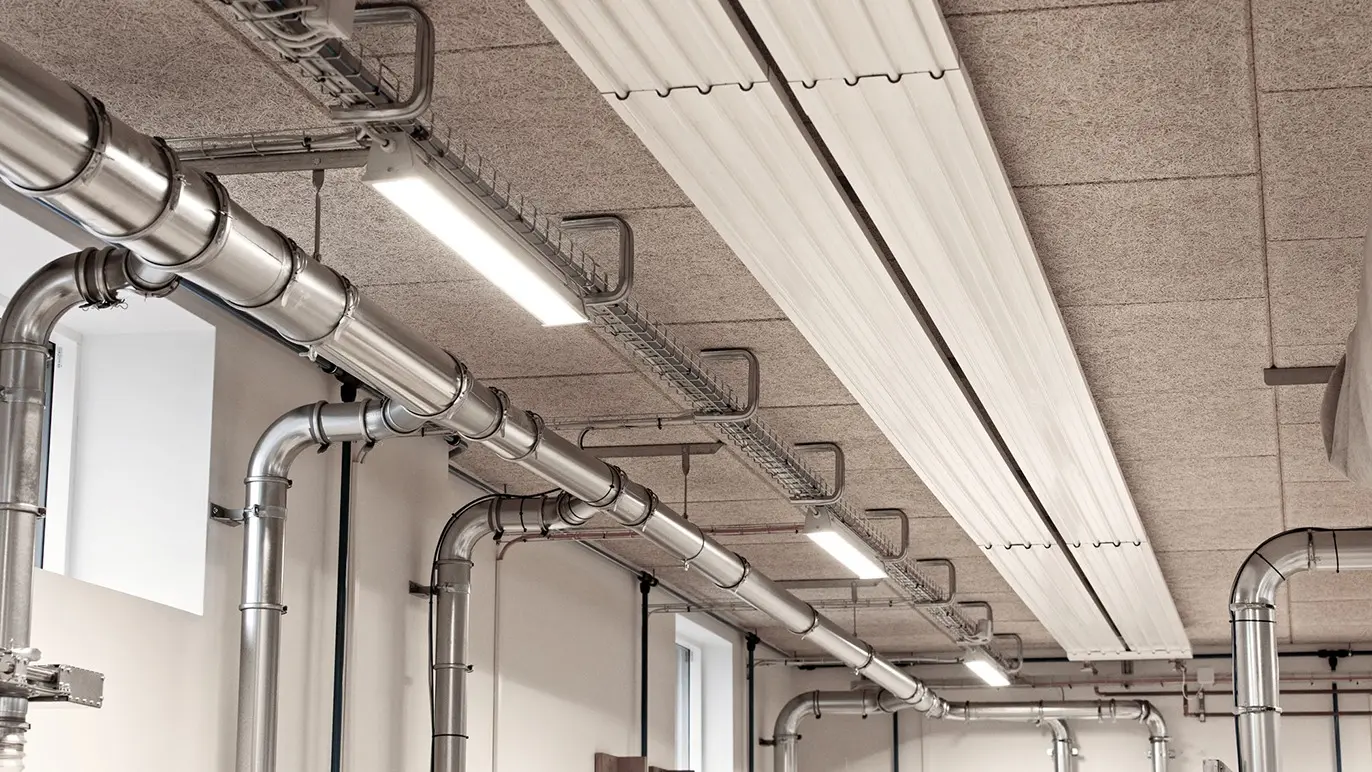 Loft med metalrør og LED-belysning i en moderne bygning.