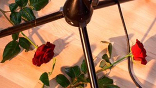 Røde roser ligger på et bord ved siden af en lampe med metalstativ.