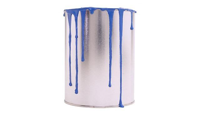 En metalbeholder med blå maling, der drypper ned ad siderne.