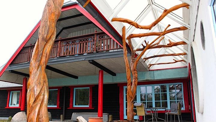 Moderne hus med trædetaljer, glasloft og farverige vinduer i en naturskøn omgivelser.
