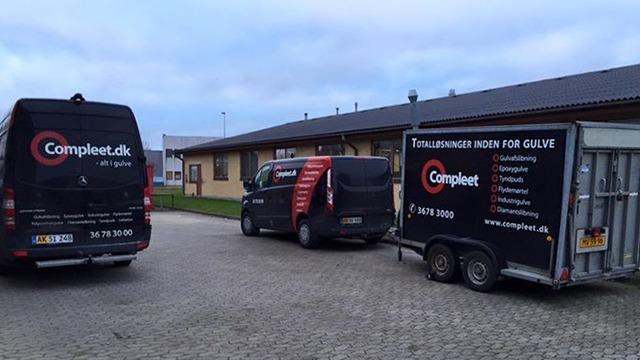 Tre biler fra Compleet.dk parkeret ved en bygning, med fokus på håndværkstjenester og udstyr til gulve.