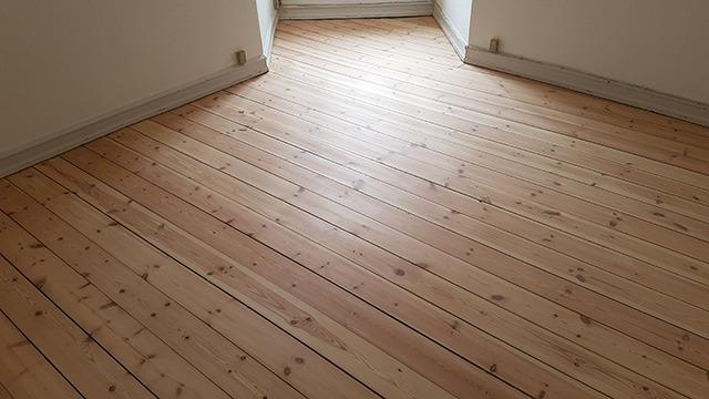 Lyst trægulv i et rum med åbning til en anden del af boligen.