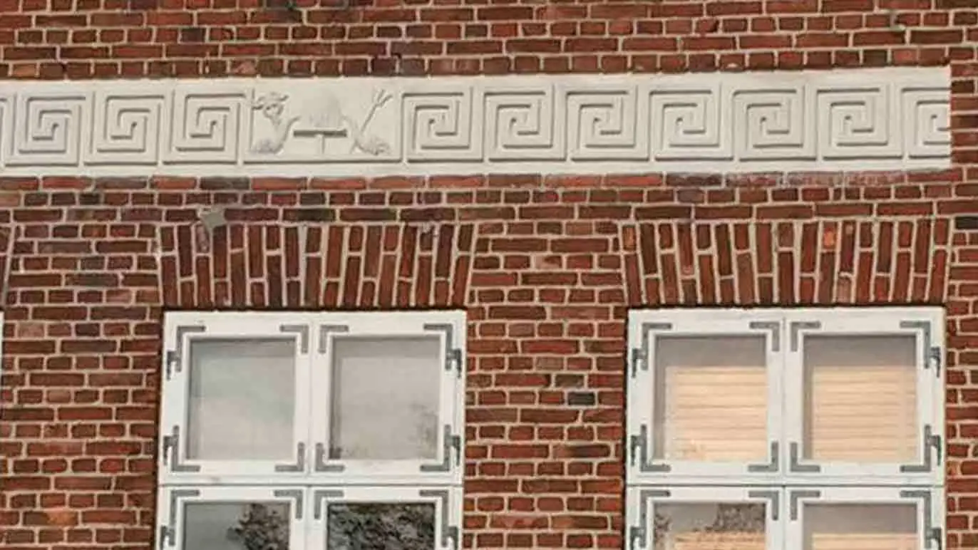 Murstensvæg med hvidt dekoration og vinduer i en bygning med klassisk arkitektur.
