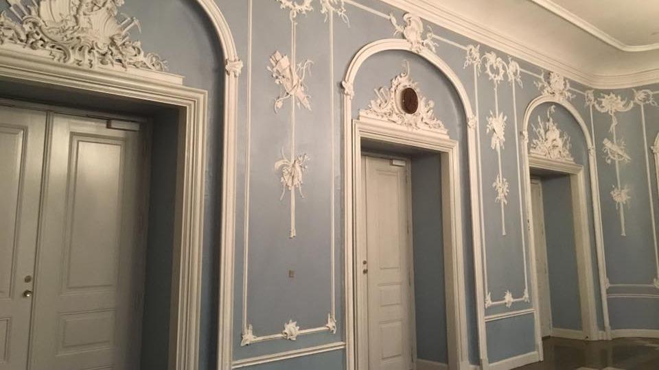 Væg med blå farve og detaljeret hvid dekoration, der viser tre døre i et elegant rum.