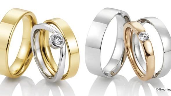 To smukke vielsesringe i guld og sølv med en diamant, præsenteret i et elegant arrangement.