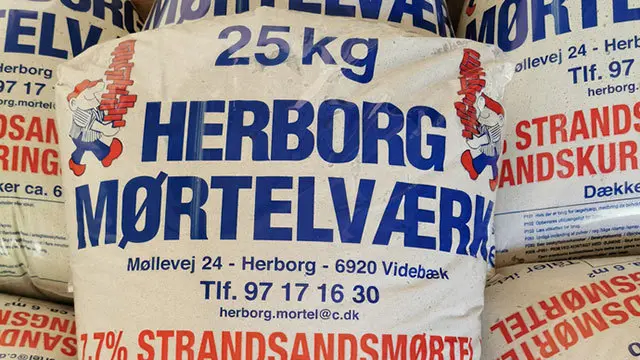 Sække med 25 kg strandsand fra Herborg Mørtelværk, med tydelig tekst og kontaktinformation.