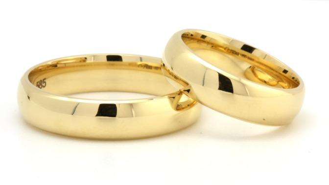 To smukke guld vielsesringe med en glat overflade, der symboliserer kærlighed og forpligtelse.
