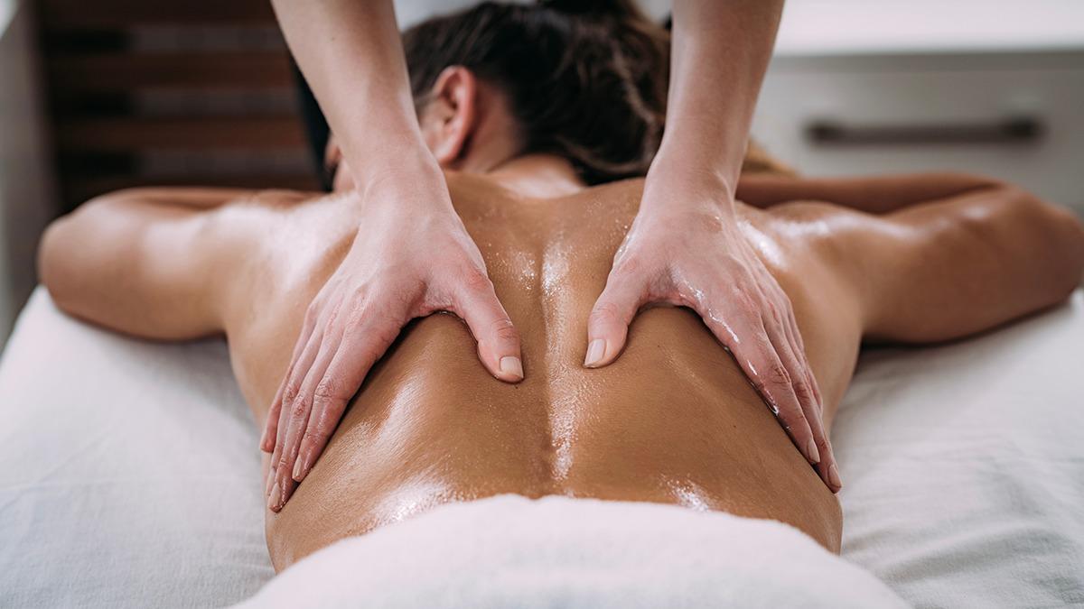 En person får en afslappende rygmassage med olie på en massagebriks.