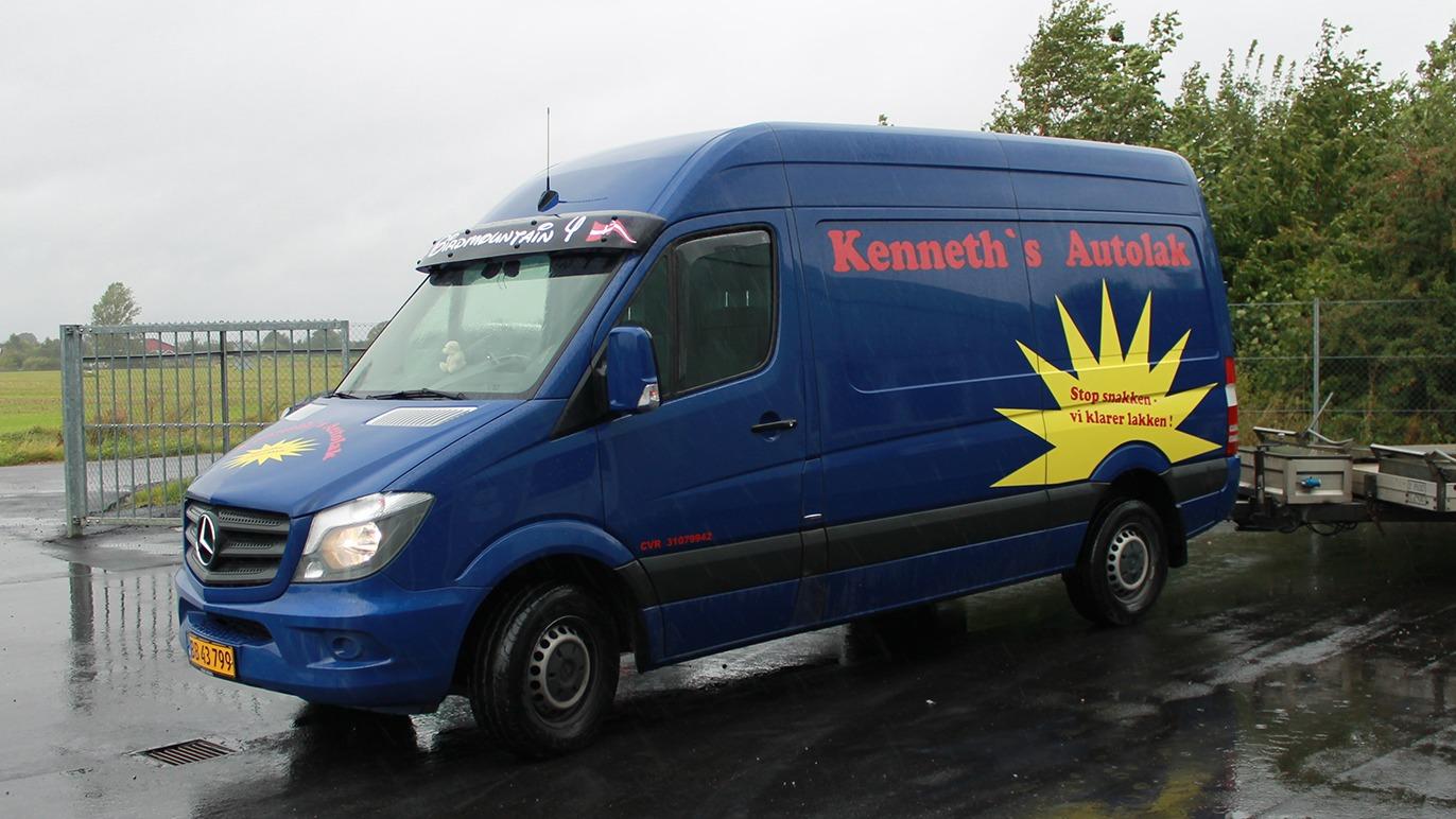 Blå varevogn med teksten "Kenneth's Anlæg" og solmotiv, parkeret ved en indkørsel.