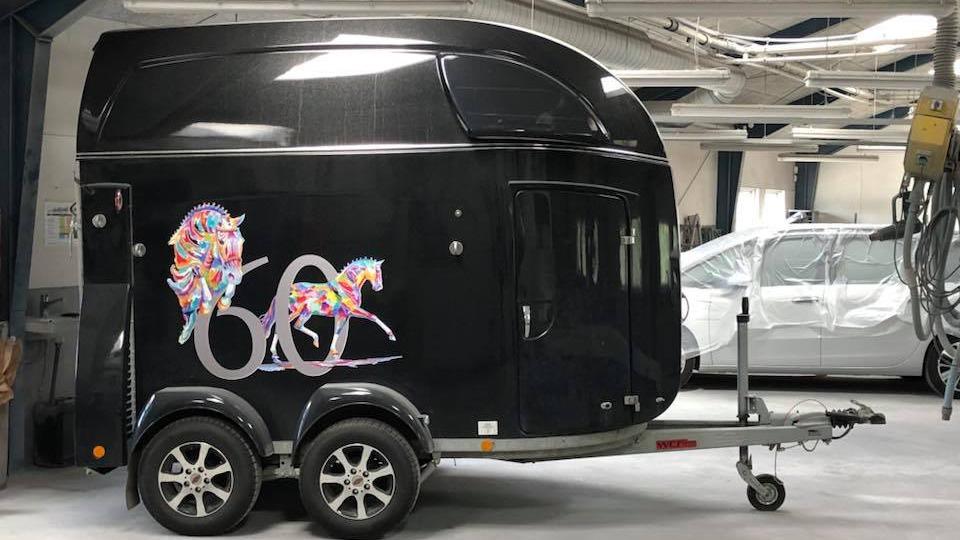 En sort trailer med farverig dekoration og nummeret 60, parkeret i en garage.