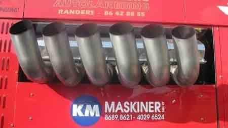 Billede af en maskine med flere metalrør, der stikker ud fra en rød maskine med teksten "KM MASKINER".