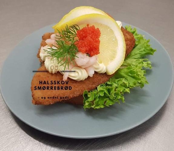 Lækkert smørrebrød med rejer, æg, citron og dild på en tallerken med salat.