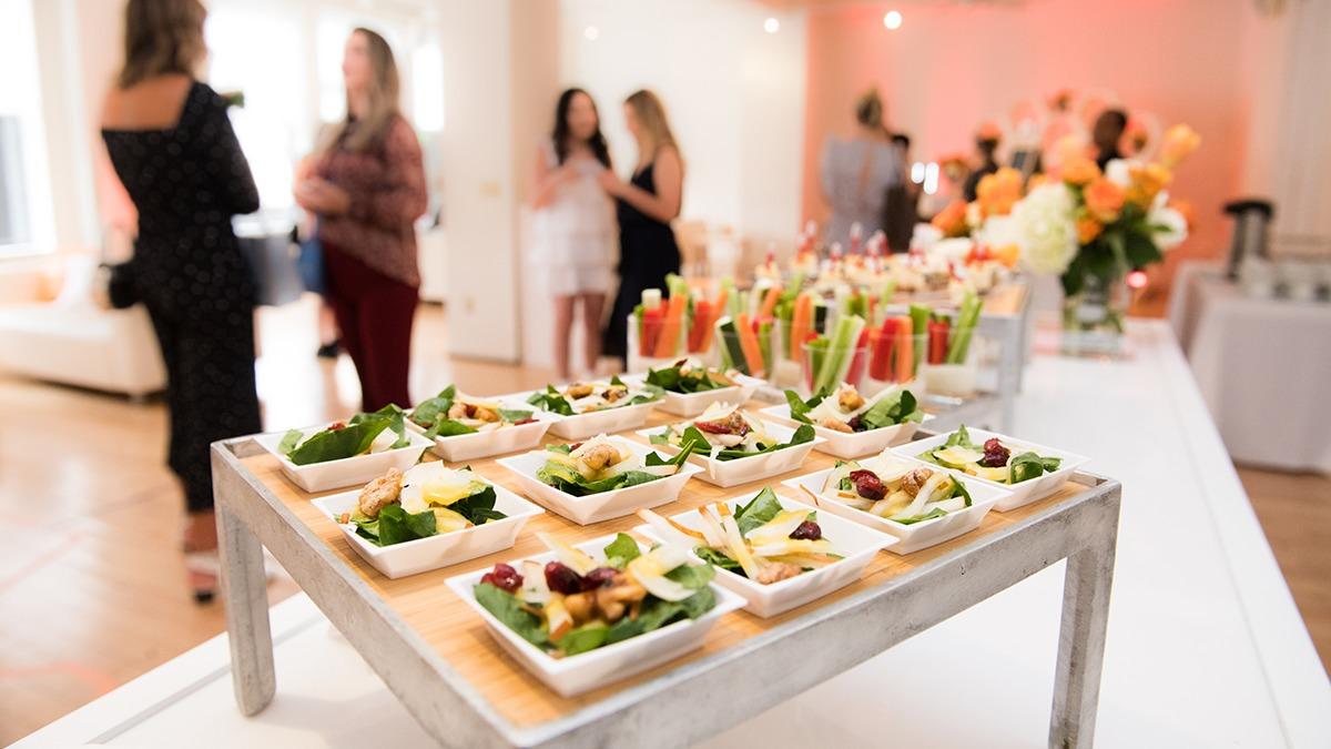 Lækre forretter præsenteret på en buffet med friske ingredienser og farverige drinks i baggrunden.