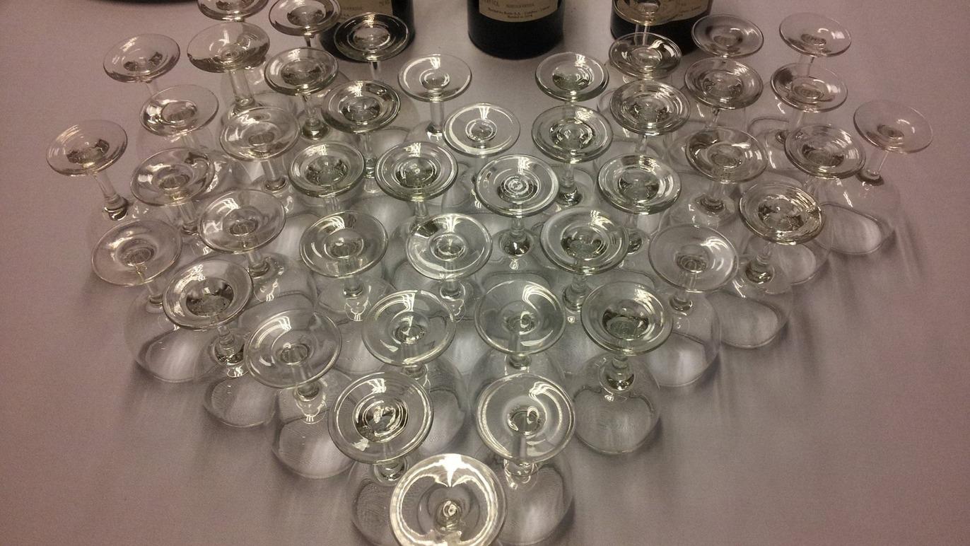 En samling af mange klare glas og flasker på et bord, arrangeret i en hjerteform.