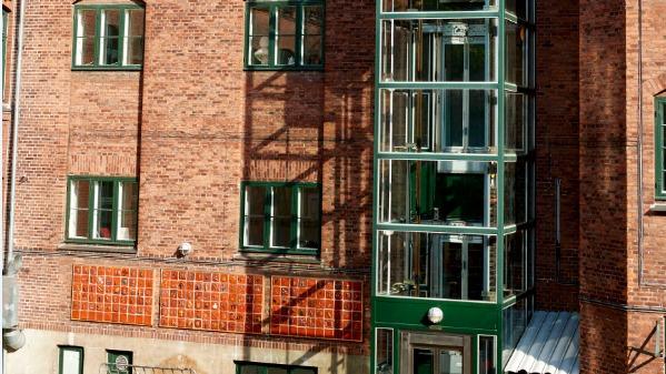 En bygning med murstensvægge og en glas elevator, der fører til de øverste etager.