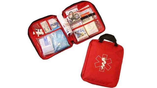 En rød førstehjælpskasse åbnet med indhold som bandager, medicin og informationsmateriale.