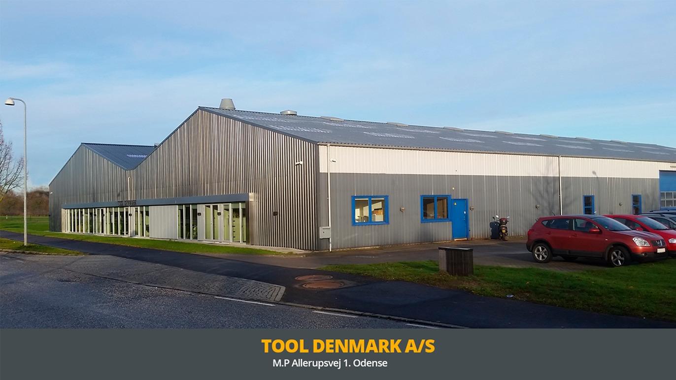 Moderne erhvervsbygning til Tool Denmark A/S med metalfacade og store vinduer i et grønt område.