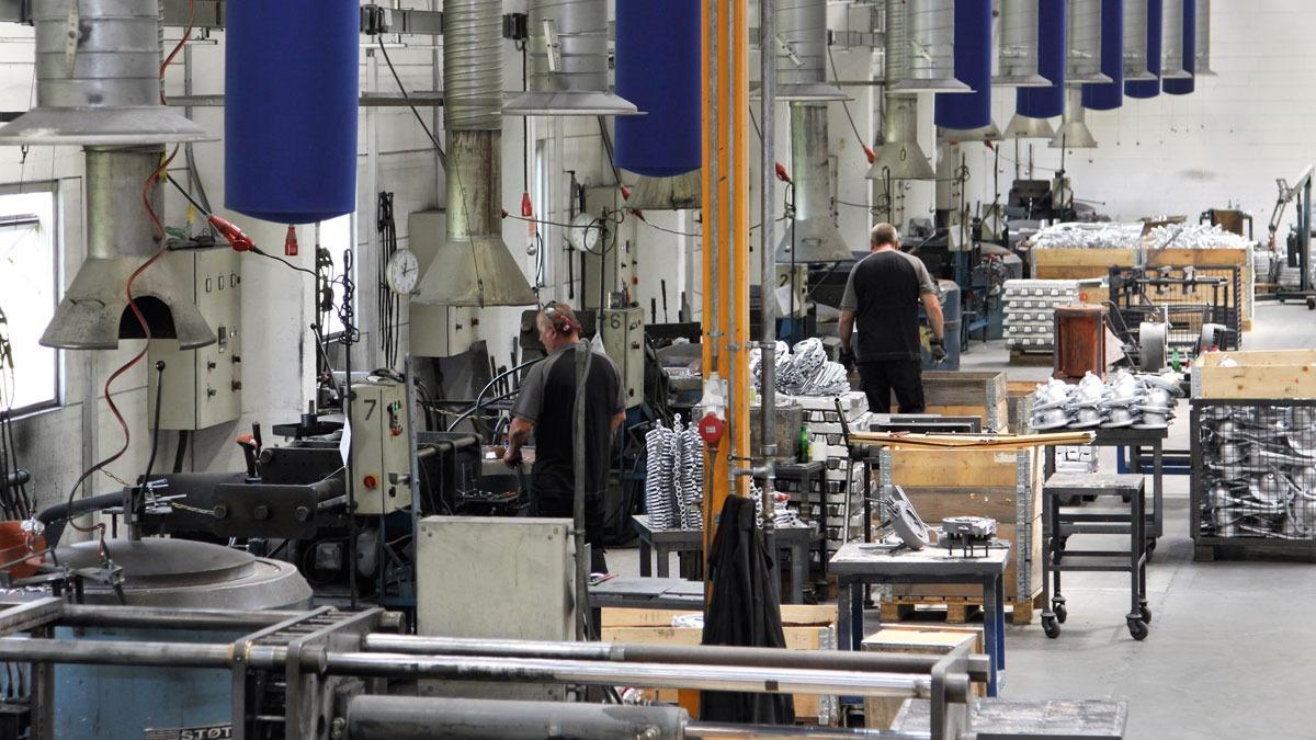 Fabriksindustri med arbejdere, maskiner og værktøjer i en stor produktionshal.