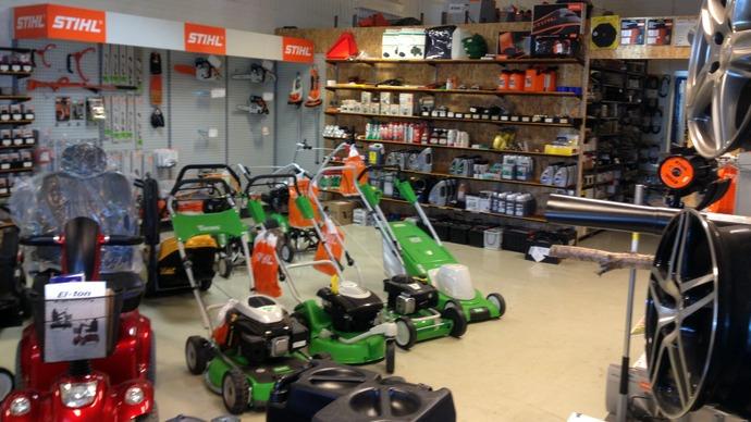 Butik med græsslåmaskiner, haveredskaber og tilbehør til havearbejde på hylderne.