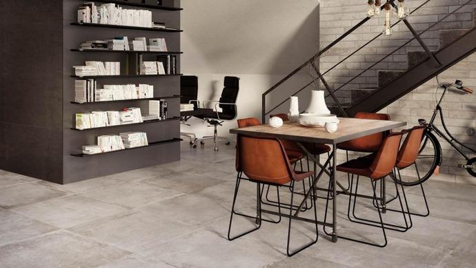 Moderne stue med et spisebord, fire stole, en bogreol og en trappe i et stilrent indretning.