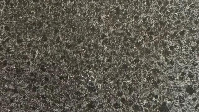 Mørk granitoverflade med fine, lyse mineraler og en struktureret, glat finish.