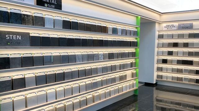 Væg med forskellige materialer som metal og sten, præsenteret i en moderne udstillingslokale.