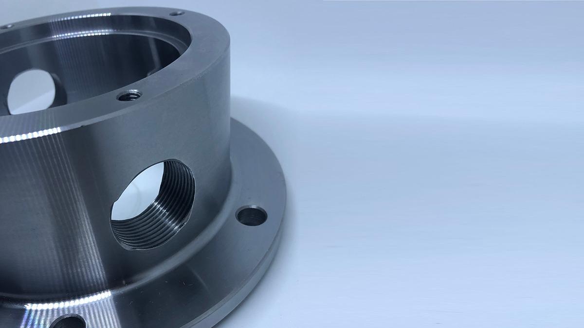 Et nærbillede af en metalflange med huller og en glat overflade, der viser detaljer i designet.