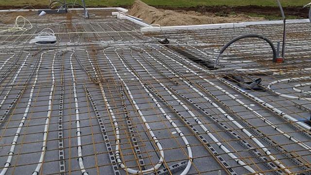 Billede af et byggeplads med varmefordelingsrør installeret i en betonplade.