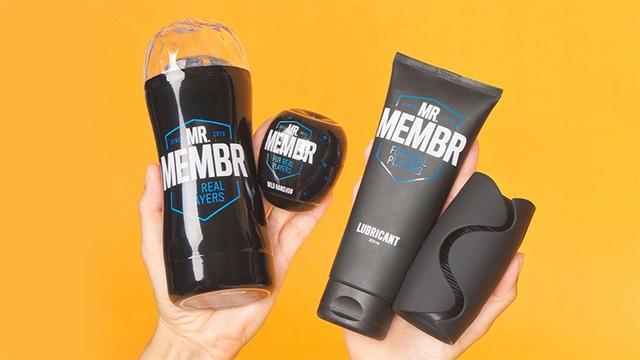 Håndholdte produkter fra Mr. Membr, herunder en kop, gel, lotion og en beholder på en orange baggrund.