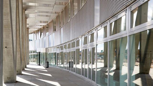 Moderne bygning med store vinduer og en buet facade, der skaber skygger på gulvet.