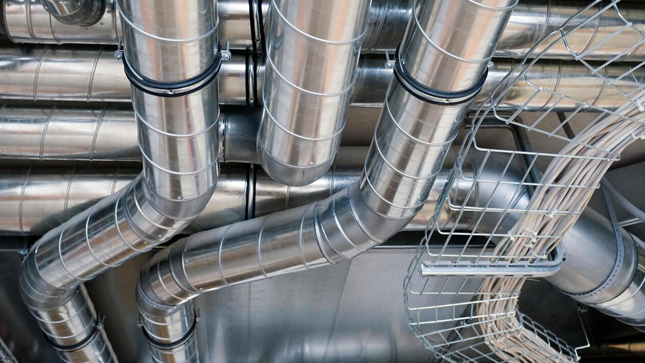 Metalrør og ventilationssystem i en bygning, der viser komplekse rørforbindelser og netværk.
