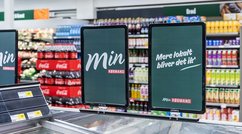 Skilt i supermarked med teksten "Min" og "Mere loyalt bliver det ikke" foran hylder med drikkevarer.