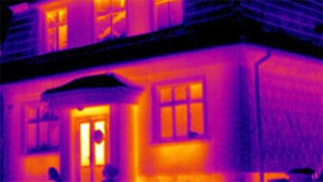 Termisk billede af et hus med varmeudslip fra vinduer og døre, der viser energitab.
