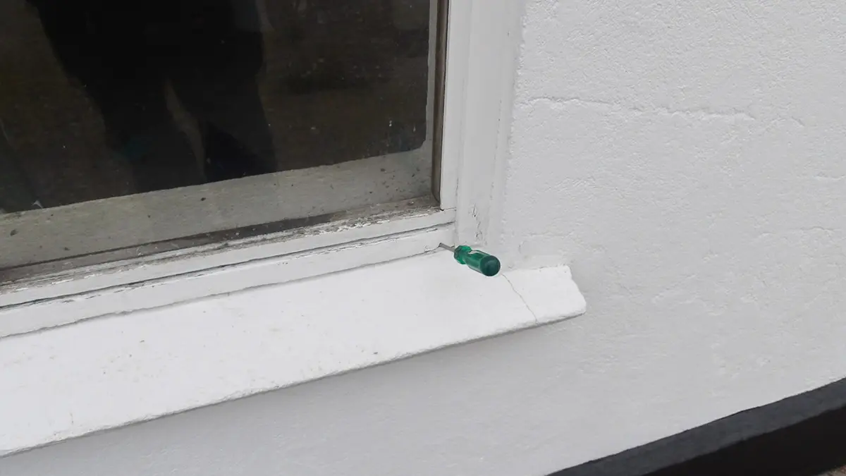 Grøn kapsel placeret på vindueskarmen ved et hvidt vindue.
