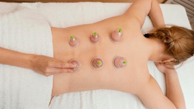 En person får cupping-behandling med glas på ryggen i et spa-miljø.