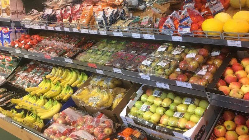 Frisk frugt og grøntsager præsenteret i en supermarkedshylde med forskellige farver og typer.