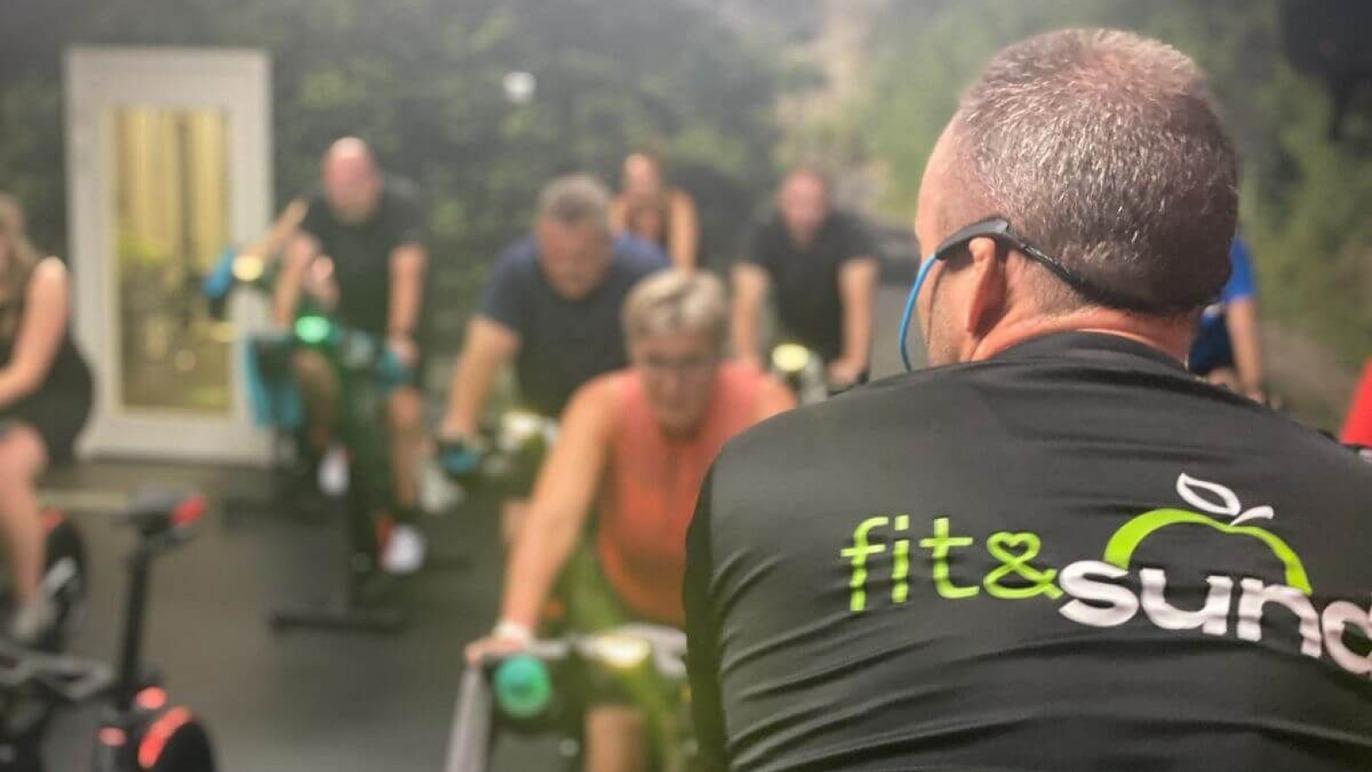 En gruppe mennesker deltager i en spinningklasse med fokus på fitness og sundhed.