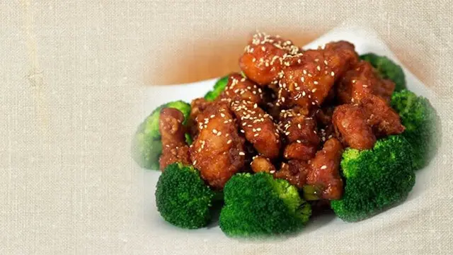 Kylling i sesamsoja med broccoli på en hvid tallerken.