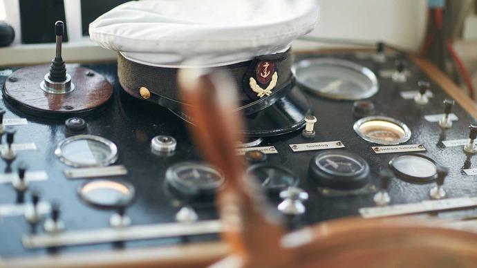 Et skibskontrolpanel med en kaptajns hat og forskellige instrumenter til navigation.