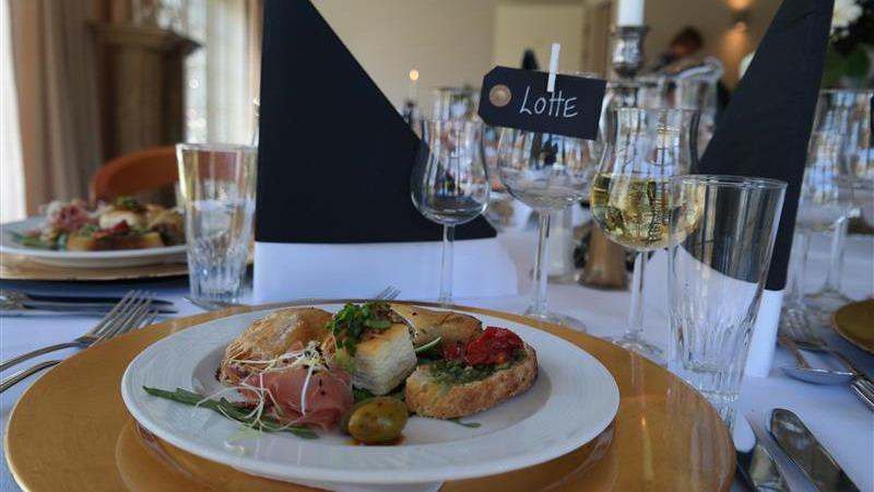 En elegant middagstallerken med forskellige retter, herunder skaldyr, grøntsager og brød, præsenteret på et festligt bord.